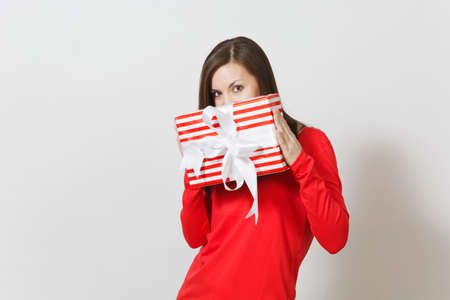 Smiling woman holding red striped present box with ribbon, bow isolated on white background. For advertisement. St. Valentine's Day, International Women's Day, Christmas, birthday, holiday conceptの写真素材