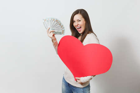 Beautiful smiling woman holding big red heart, bundle of cash money dollars on white background. Copy space for advertisement. Place for text. St. Valentine's Day or International Women's Day conceptの写真素材