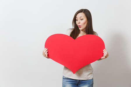 Beautiful young smiling woman holding big red heart in hands isolated on white background. Copy space for advertisement. With place for text. St. Valentine's Day or International Women's Day conceptの写真素材