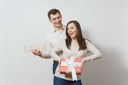 Cute couple in love. Man, woman with wooden word Love, present box with gift isolated on white background. For advertisement. St. Valentine's Day, International Women's Day, birthday, holiday conceptの写真素材