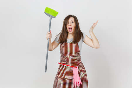 Young fun crazy dizzy loony wild screaming housewife tousled hair in striped apron squeegee pink gloves in pocket isolated on white background. Mad witch woman broom. Copy space for advertisementの写真素材