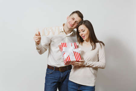 Cute couple in love. Man, woman with wooden word Love, present box with gift isolated on white background. For advertisement. St. Valentine's Day, International Women's Day, birthday, holiday conceptの写真素材