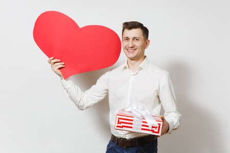 Young handsome smiling man in shirt holding red present box with gift isolated on white background. Copy space for advertisement. St. Valentines Day, International Womens Day birthday holiday conceptの写真素材