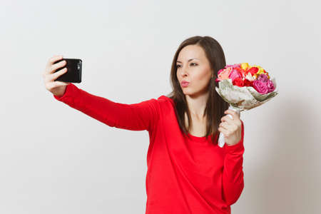 Woman doing duck face selfie on mobile phone with bouquet of beautiful flowers isolated on white background. Copy space for advertisement. St. Valentines Day, International Womens Day, holiday conceptの写真素材