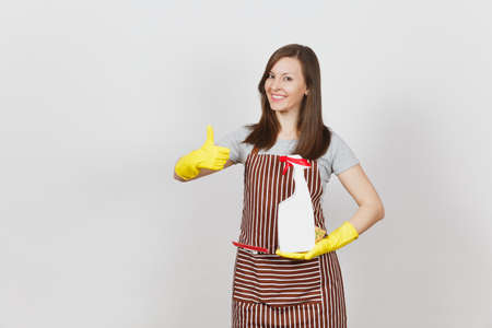 Housewife in yellow gloves striped apron cleaning rag squeegee in pocket isolated on white background. Housekeeper woman showing thumb up holding spray bottle with cleaner liquid. Bottle copy spaceの写真素材