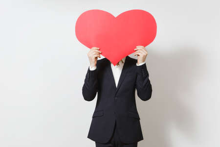 Young man in suit covering face by big red heart isolated on white background. Copy space, advertisement. Place for text. St. Valentine's Day, International Women's Day, birthday, holiday conceptの写真素材