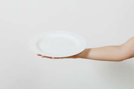 Close up of female hand horizontal holding white round plate isolated on white background. Kitchen utensils concept. Copy space for advertisementの写真素材