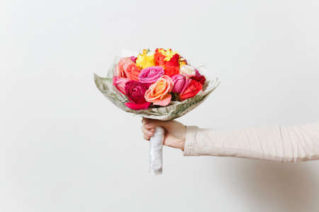 Women hand holding beautiful bouquet of colorful roses, different red, yellow, orange flowers. Isolated on white background. St. Valentine's Day or International Women's Day, holiday conceptの写真素材