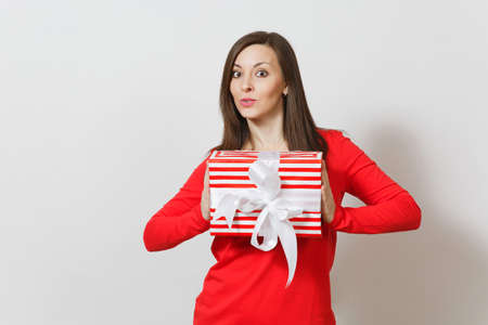 Smiling woman holding red striped present box with ribbon, bow isolated on white background. For advertisement. St. Valentine's Day, International Women's Day, Christmas, birthday, holiday conceptの写真素材