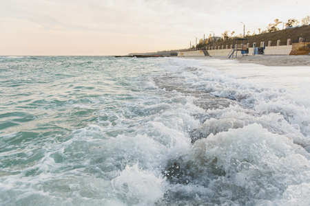 Beautiful sea landscape. Surf Azure waves break on coastline beach, forming a foam and a splash.