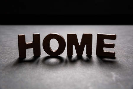 Word Home of wooden letters on the dark texture with a black background with backlight. Lighting effect.の写真素材