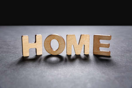 Word Home of wooden letters on the dark texture with a black background with backlight. Lighting effect.の写真素材