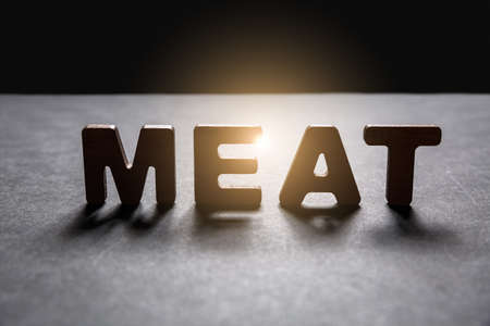 Word Meat of wooden letters on the dark texture with a black background with backlight. Lighting effect.の写真素材