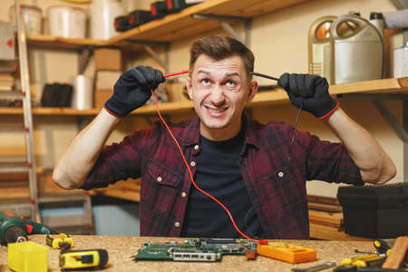 Multimeter for electrician. Crazy aggressive batty mad fun young man in plaid shirt, digital...