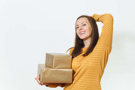 Beautiful caucasian fun young happy birthday woman in yellow clothes holding two golden gift boxes with present, celebrating and enjoying holiday party on white background isolated for advertisementの写真素材