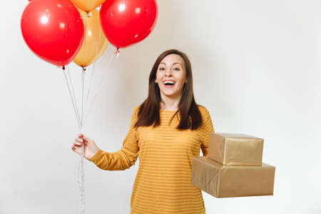 Beautiful caucasian fun young happy woman in yellow clothes, holding birthday red balloons, golden gift boxes with present, celebrating holiday party on white background isolated for advertisementの写真素材