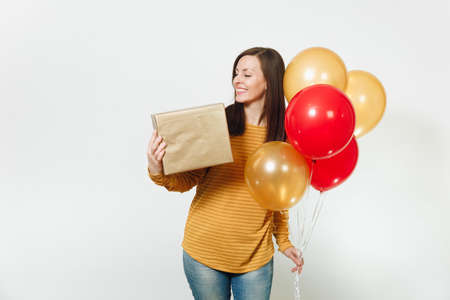 Beautiful caucasian fun young happy woman in yellow clothes, holding birthday red balloons, golden gift boxes with present, celebrating holiday party on white background isolated for advertisementの写真素材