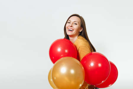 Beautiful caucasian young happy woman in long plaid checkered dress with shy charming smile, red, yellow golden balloons, celebrating birthday, on white background isolated. Holiday, party conceptの写真素材