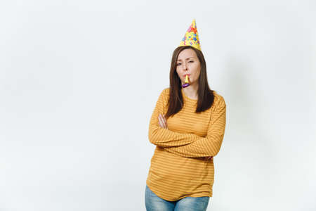 Pretty caucasian sad young woman in yellow clothes and birthday party hat with brown long hair, playing pipe, celebrating holiday alone without present on white background isolated for advertisementの写真素材