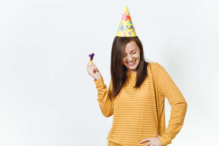 Beautiful caucasian fun young happy woman in yellow clothes and birthday party hat with brown long...