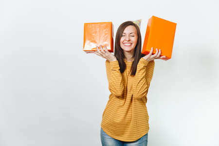 Beautiful caucasian fun young happy woman in yellow clothes, birthday party hat holding orange gift...