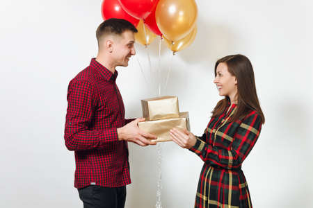 Beautiful young happy smiling couple in love. Woman and man holding golden gift boxes with present...