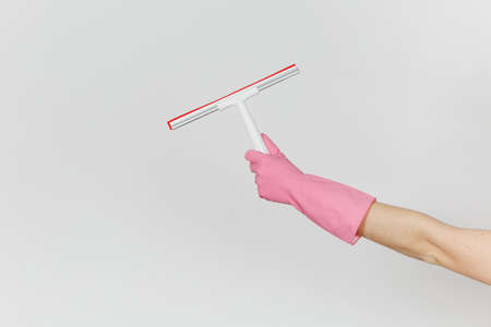 Close up of female hand in pink gloves horizontal holds white squeegee for surface cleaning with red...