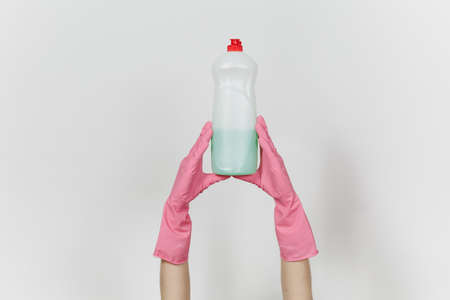 Close up of female hands in pink gloves holds white bottle with green cleaner liquid for washing dishes with place for text isolated on white background. Cleaning supplies concept. Copy space for ad.の写真素材