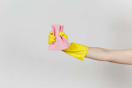 Close up of female hand in yellow gloves holds and squeezes pink absorbent napkin for cleaning and...