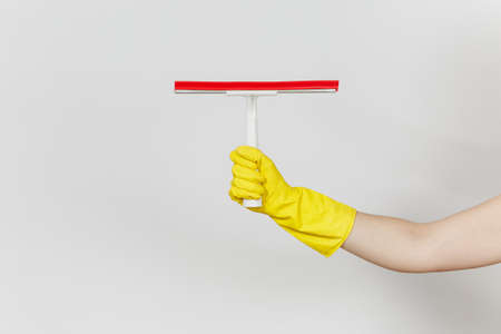 Close up of female hand in yellow gloves horizontal holds white squeegee for surface cleaning with...
