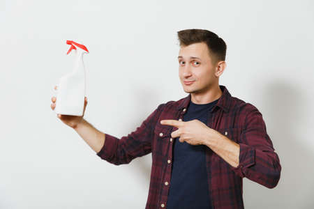 Studio portrait handsome caucasian smiling young man in shirt with white bottle sprayer cleaner isolated on white background. Copy space for advertisement. With place for text. Housekeeping conceptの写真素材