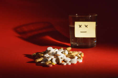 Medication white colorful tablets pills arranged abstract on dark red color background. Capsule vial...