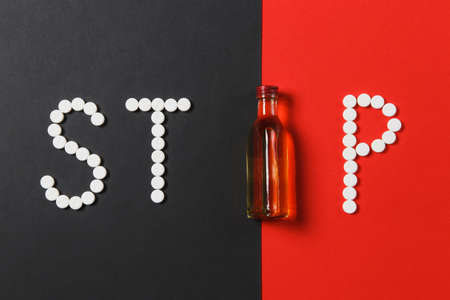 Medication white round tablets in word Stop. Creative composition with message Stop Drinking bottle...