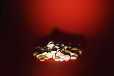 Medication white colorful round tablets arranged abstract on red color background. Aspirin, capsule...