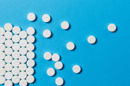 Medication white round tablets arranged abstract isolated on blue color background. Aspirin pills...