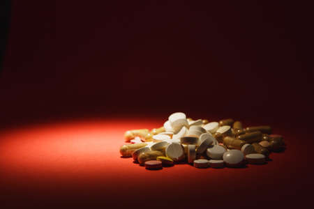 Medication white colorful round tablets arranged abstract on red color background. Aspirin, capsule...