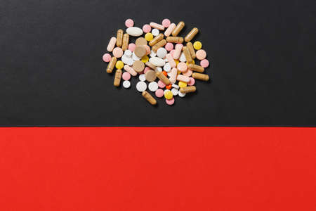 Medication white colorful round tablets arranged abstract on red black background. Aspirin, capsule pills for design. Health, treatment, choice healthy lifestyle concept. Copy space for advertisementの写真素材