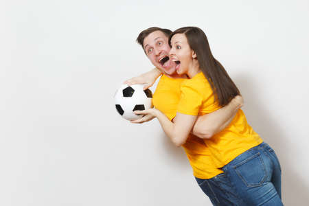 Fun crazy cheerful emotional young couple, woman, man, football fans in yellow uniform cheer up...