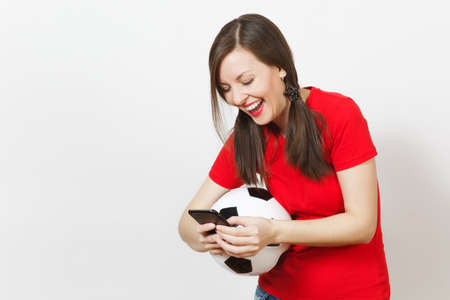 European young angry screaming woman, football fan or player in yellow uniform send sms on mobile phone, hold soccer ball isolated on white background. Sport, play football, healthy lifestyle conceptの写真素材