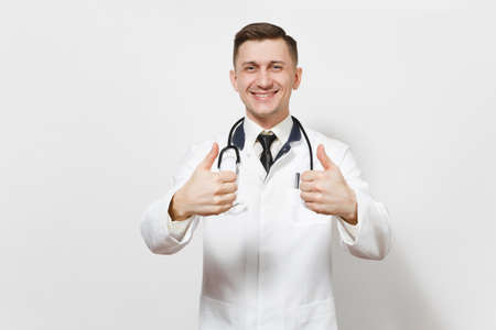 Smiling confident handsome young doctor man isolated on white background. Male doctor in medical uniform stethoscope showing thumbs up.の写真素材