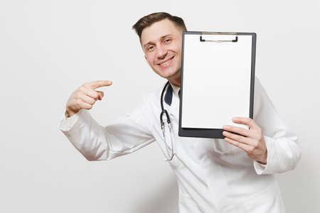 Smiling young doctor man isolated on white background. Male doctor in medical uniform, stethoscope health card on notepad folder. Blank sheet.の写真素材