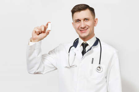 Smiling experienced handsome young doctor man isolated on white background. Male doctor in medical uniform, stethoscope holding bottle with white pills.の写真素材