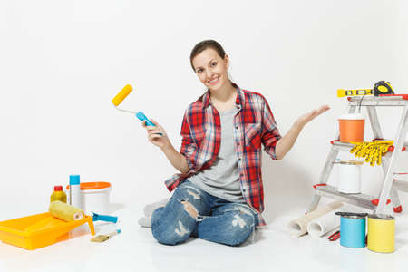 Woman in casual clothes sitting on floor with paint roller, instruments for renovation apartment isolated on white background.の写真素材