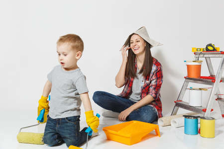 Mother and small son with instruments for renovation apartment room isolated on white background. Wallpaper, gluing accessories, painting tools. Boy woman repairing home. Parenthood childhood conceptの写真素材