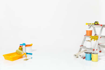 Instruments for renovation apartment room isolated on white background. Wallpaper and accessories for gluing, painting tools. Colorful paint cans. Concept of repair home. Copy space for advertisementの写真素材