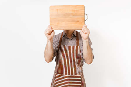 Young man chef or waiter in striped brown apron, shirt cover face with wooden cutting board, knife...