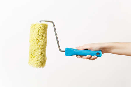Close up of female hand horizontal holds paint roller for wall painting isolated on white background. Instruments for renovation apartment room. Repair home concept. Copy space for advertisementの写真素材