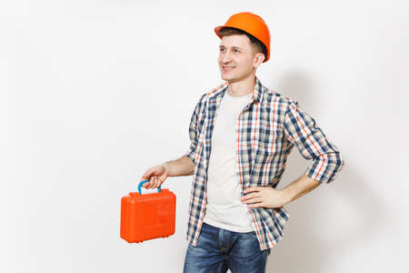 Young smiling man in protective hardhat holding case with instruments or toolbox and looking aside on copy space isolated on white background. Tools for renovation apartment room. Repair home conceptの写真素材
