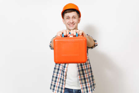 Young smiling handsome man in protective orange hardhat holding case with instruments or toolbox isolated on white background. Instruments, tools for renovation apartment room. Repair home conceptの写真素材