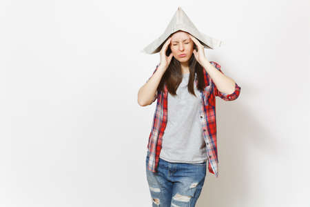Young exhausted woman in newspaper hat with closed eyes keeping hands near face isolated on white...